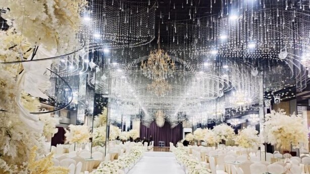 A wedding venue with a white aisle, floral arrangements, and a chandelier. - Tongxilai Hotel (Jingyan)