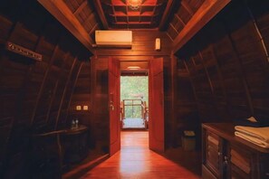 A wooden interior hallway leading to a door with a view of the outdoors. - Rostika Hotel Sekumpul (Sawan)