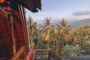 A wooden building with a balcony overlooking a landscape of palm trees and mountains. - Rostika Hotel Sekumpul (Sawan)