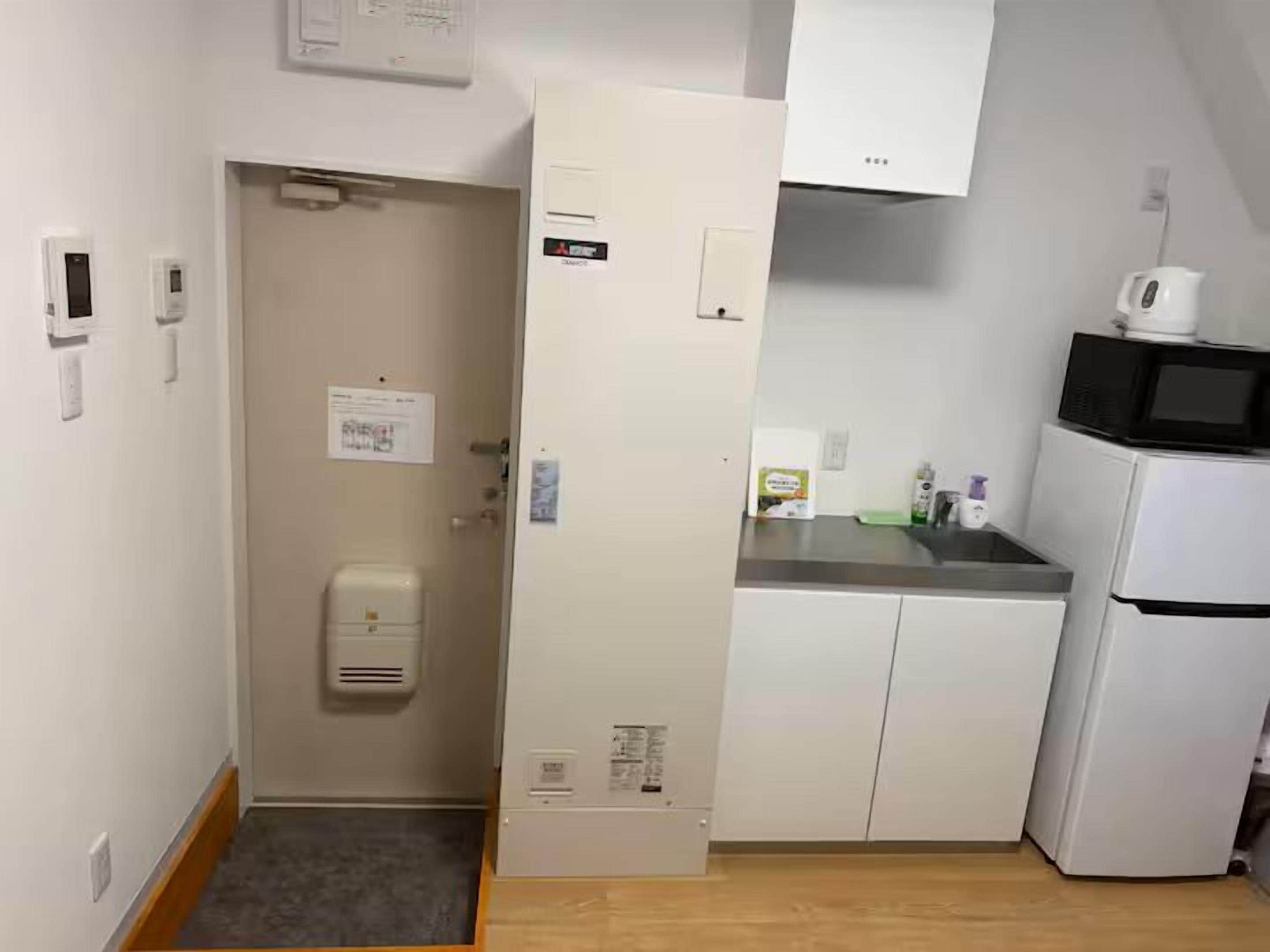 Una cocina compacta con microondas, refrigerador y un lavamanos pequeño.