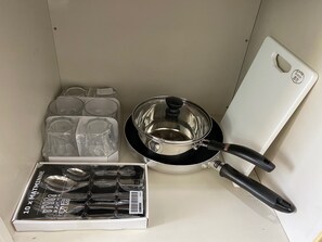 A kitchen area with a stove, a pot, a cutting board, and a box of utensils. - Quartier Blanc Yoga (Tokyo)