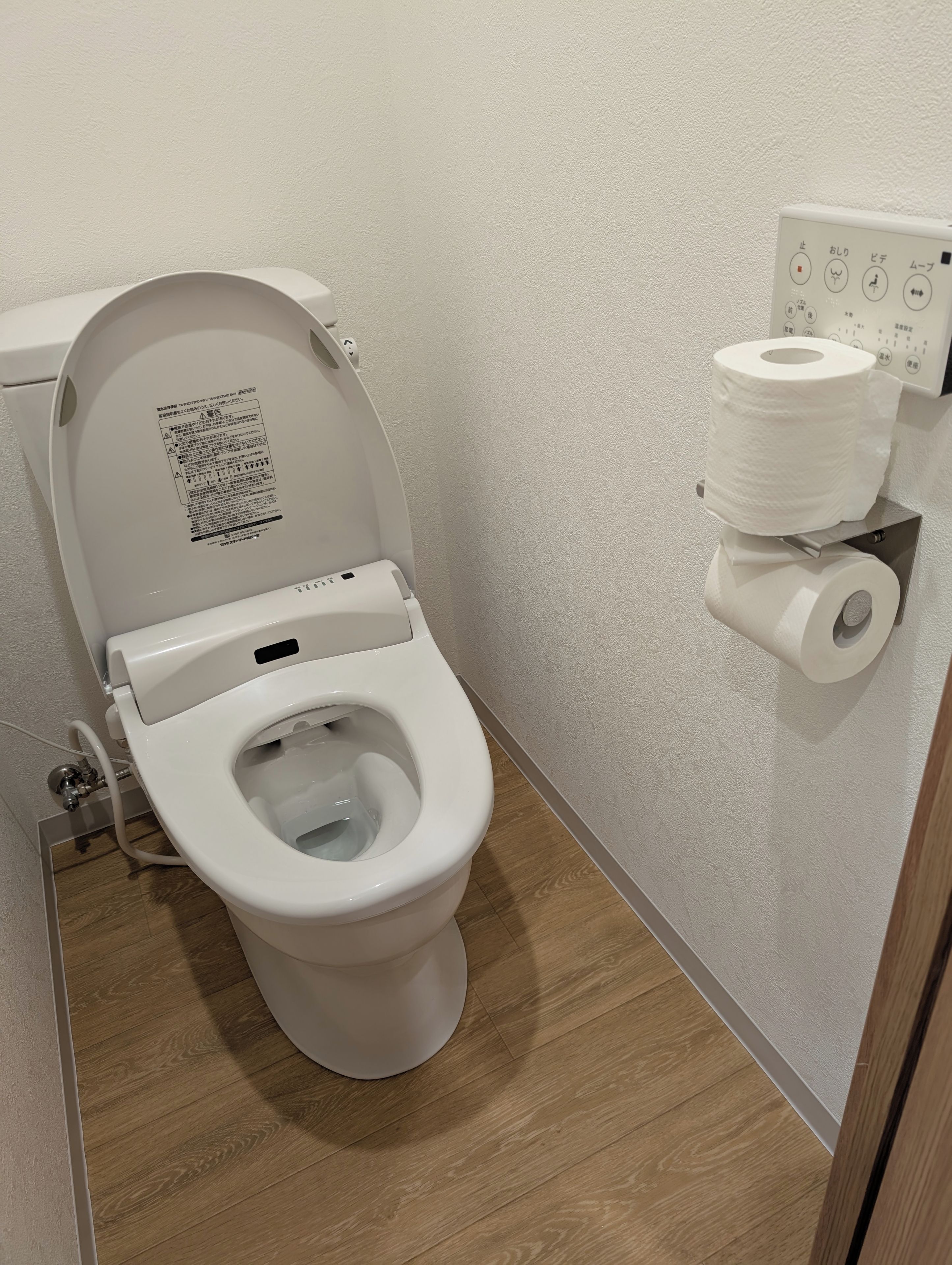 A toilet with a control panel and a toilet paper holder.