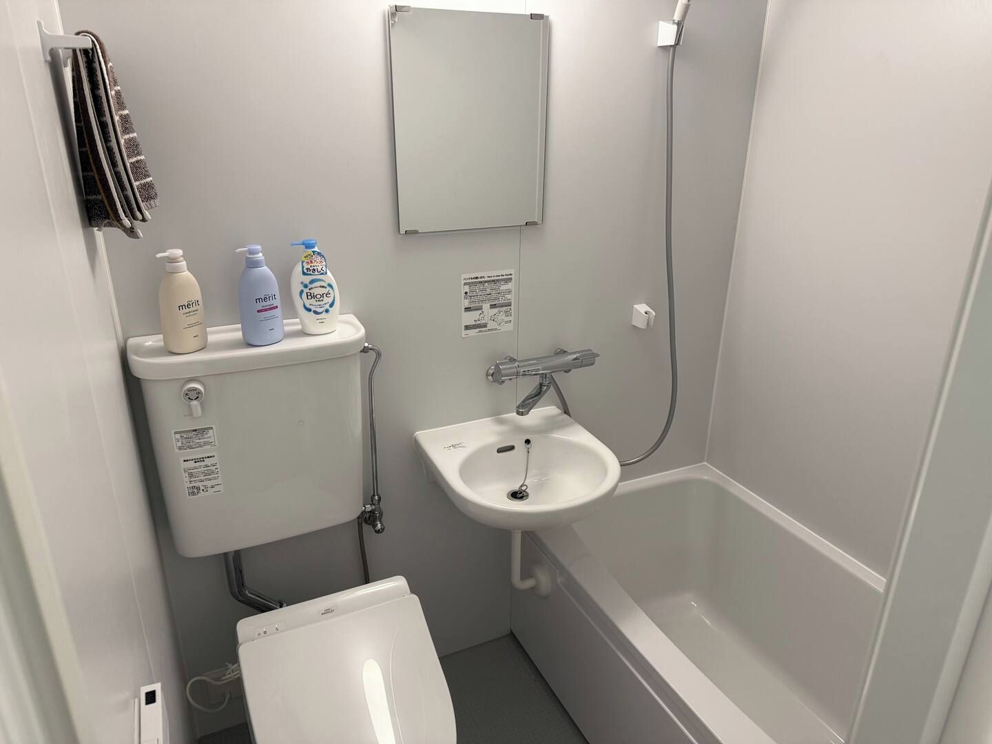 A compact bathroom with a toilet, bidet, sink, and bathtub.