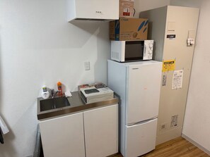 A compact kitchen with a microwave, refrigerator, and a small countertop. - Quartier Blanc Yoga (Tokyo)
