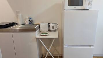 A kitchenette with a microwave, kettle, and a small table with a kettle and a box of tea bags.
