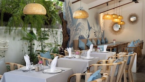 A restaurant with wicker furniture, white tablecloths, and hanging rattan lamps. - The Urban  (Siem Reap)