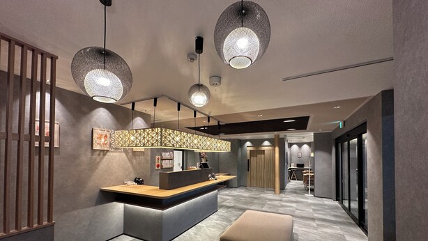 Un moderno vestíbulo de hotel con mostrador de recepción, zona de estar e iluminación decorativa.