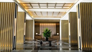 A modern lobby with a checkered floor, a central plant, and vertical wooden panels. - Hoiana Residences (Da Nang)