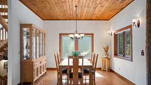 A dining area with a wooden table and chairs, a chandelier, and a large window with a view of trees. - Meridian Magic-Fantastic 4BD home, Dog friendly (Skyland & Surrounding Areas)