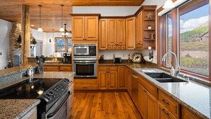 A kitchen with wooden cabinets, granite countertops, a built-in oven, and a large window offering a view of the outdoors. - Meridian Magic-Fantastic 4BD home, Dog friendly (Skyland & Surrounding Areas)