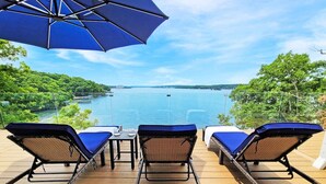 A deck with three lounge chairs and a table, overlooking a body of water and greenery. - *NEW* TV-Featured Mansion / Waterfront / Dock / Golf Green / Games (Sunrise Beach)