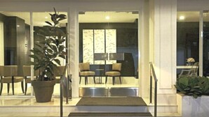 A modern interior with a seating area, a large potted plant, and a staircase leading to an upper level. - Le Mansion Senopati Hotel (Jakarta)