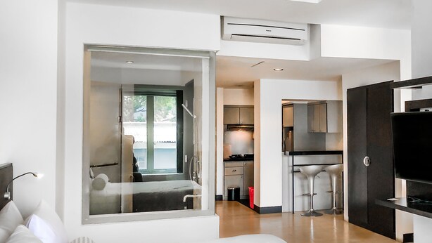 A modern hotel room with a large bed, a TV, and a kitchenette. - Le Mansion Senopati Hotel (Jakarta)