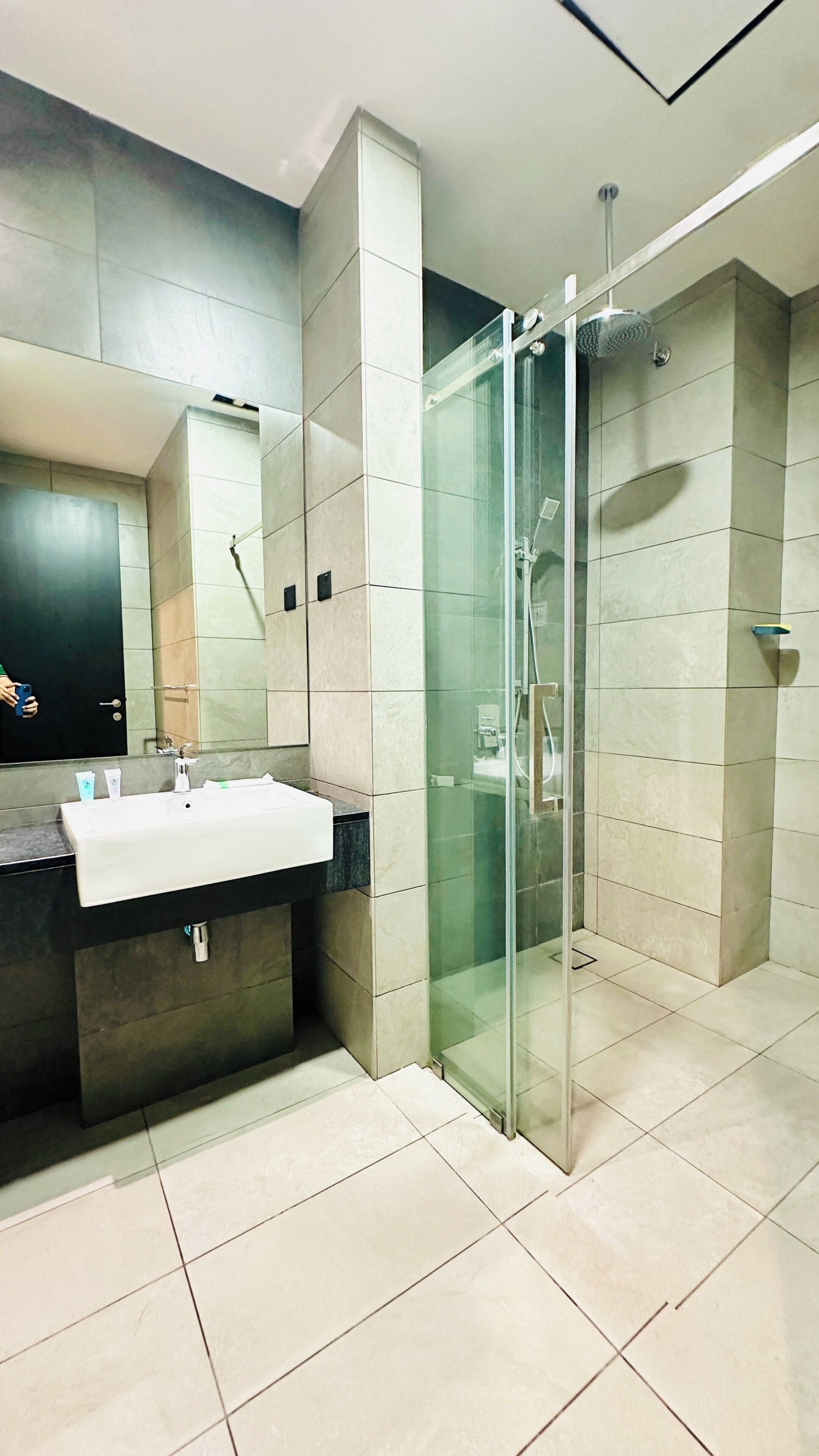 A modern bathroom with a glass-enclosed shower, a white sink, and a large mirror.