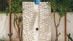 A stone wall with a door, surrounded by cacti and palm trees. - Villa Bocce (Canggu)