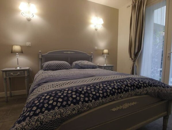 A bedroom with a bed, two bedside lamps, a headboard, and a window with curtains. - Marais, Rue Volta, sleeps 4, with air conditioning – 1 bedroom (Paris)