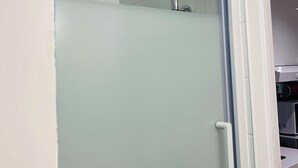 A modern bathroom with a glass-enclosed shower, a white sink, and a microwave visible in the background. - Arts-et-Métiers: 5 minutes walk from rue Rambuteau (Paris)