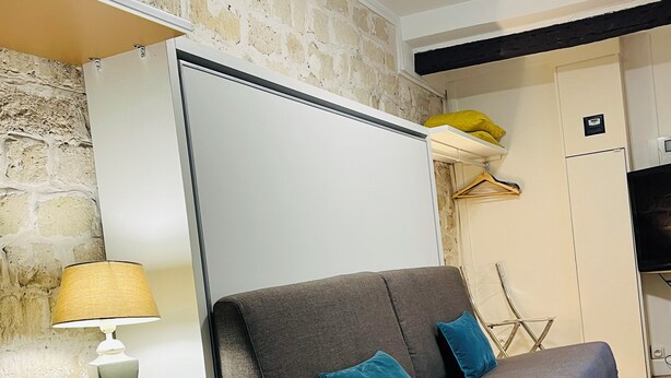A modern room with a sofa, a small table with a lamp, a brick wall, and a wardrobe. - Arts-et-Métiers: 5 minutes walk from rue Rambuteau (Paris)
