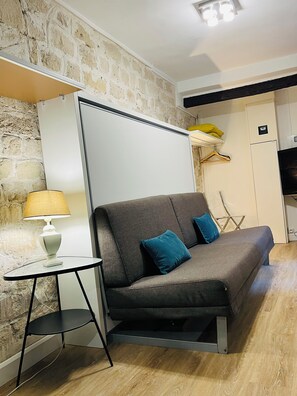 A modern room with a sofa, a small table with a lamp, a brick wall, and a wardrobe. - Arts-et-Métiers: a 5-minute walk from Rue Rambuteau (Paris)