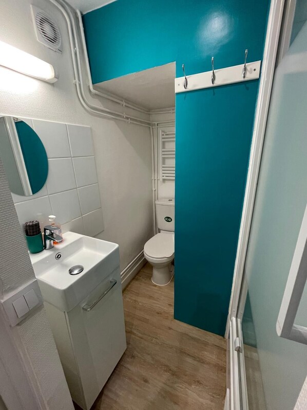 A compact bathroom with a white sink, a toilet, and a shower area. - Arts-et-Métiers: a 5-minute walk from Rue Rambuteau (Paris)