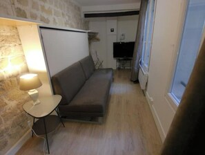 A small, cozy living area with a sofa, a lamp, and a television in the background. - Arts-et-Métiers: 5 minutes walk from rue Rambuteau (Paris)