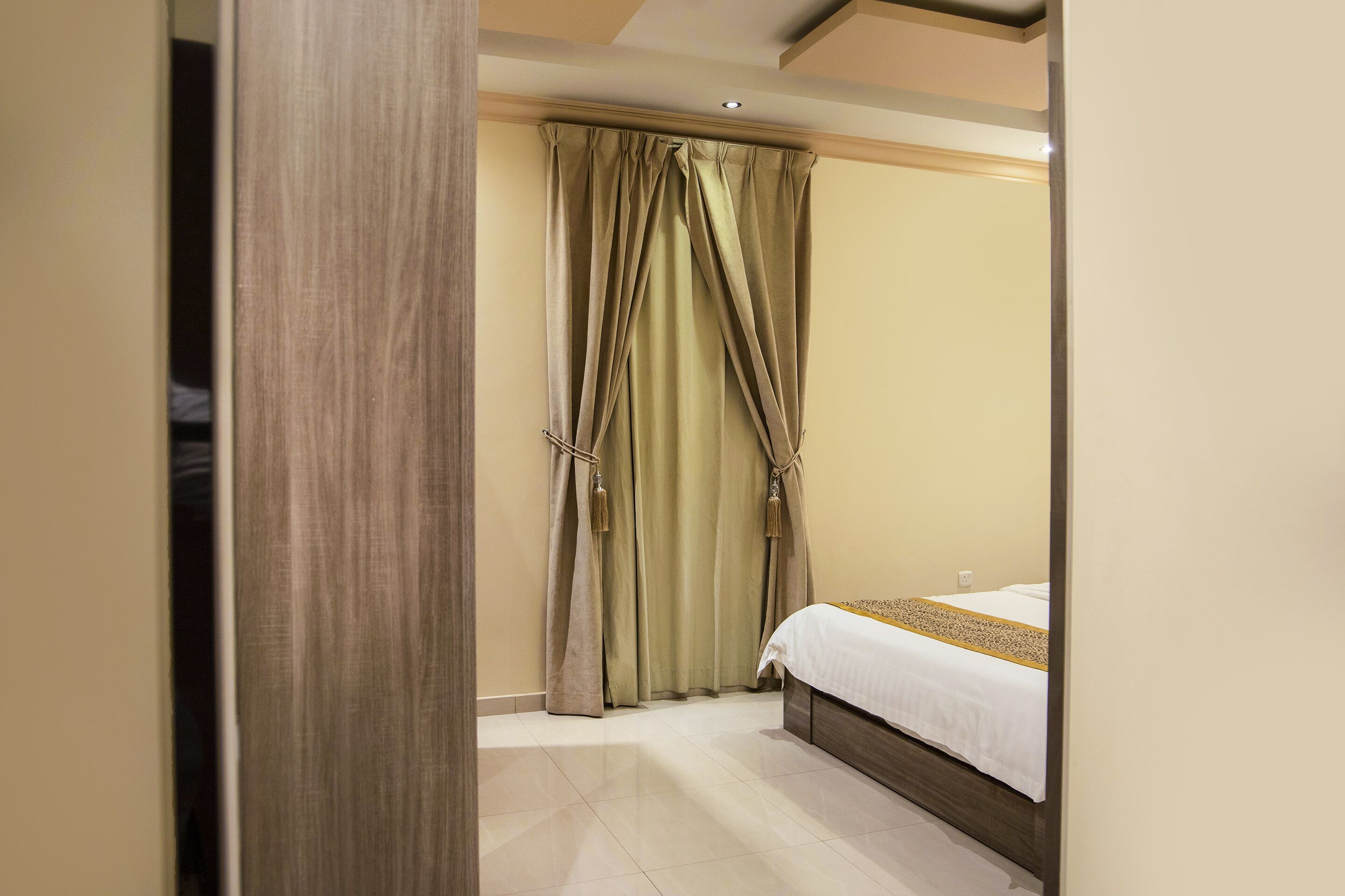Un dormitorio con cama, cortinas y una puerta de madera.