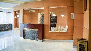 A modern reception area with a wooden reception desk, a seating area, and a display of framed certificates. - Wasan Suites Furnished Apartments (Riyadh)
