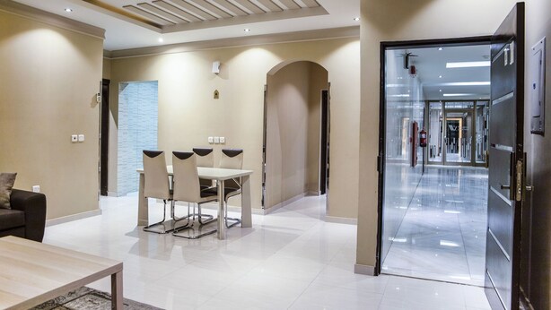 A modern hotel lobby with a dining area, a sofa, and a reception desk. - Wasan Suites Furnished Apartments (Riyadh)