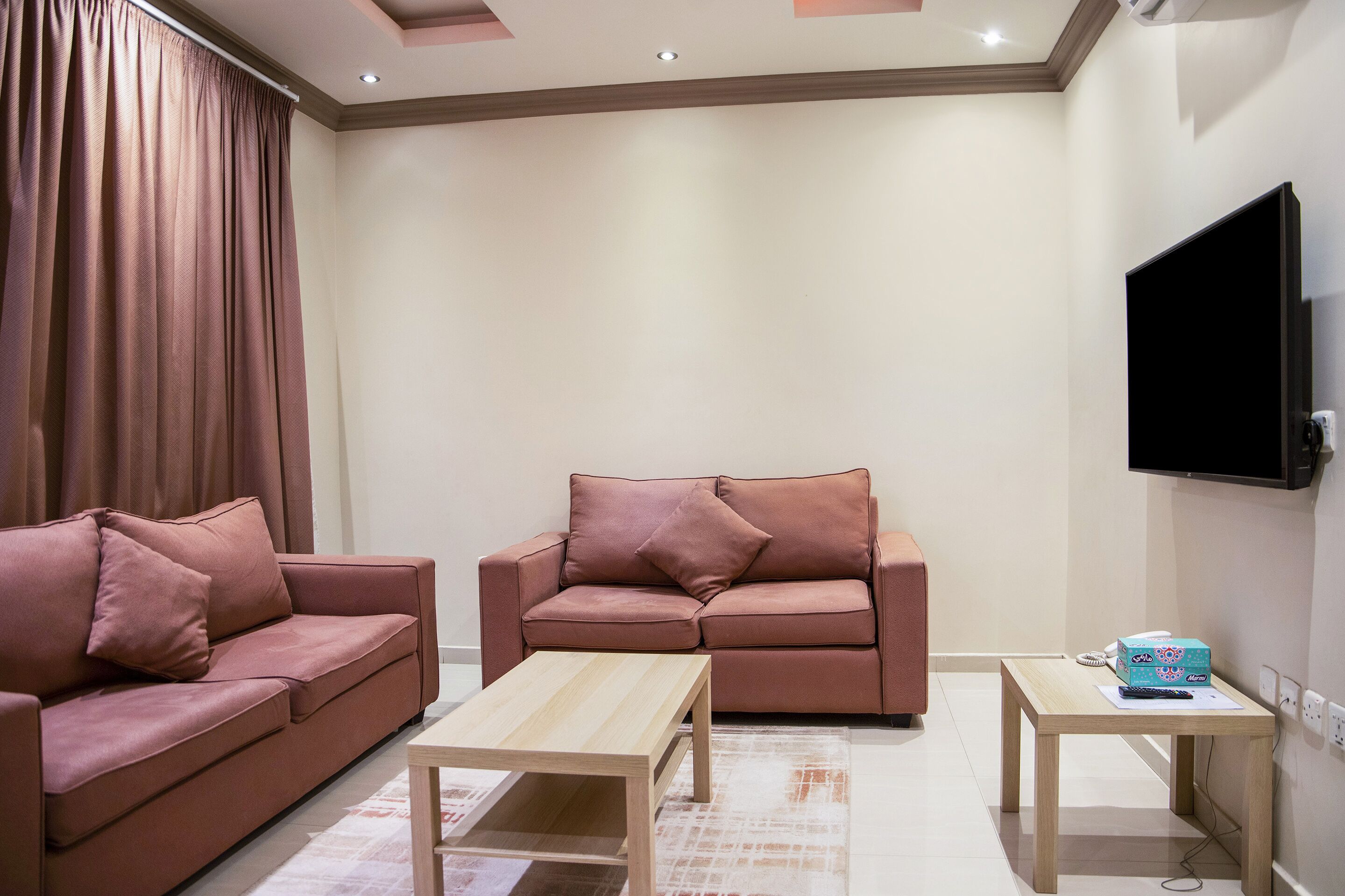 A living room with two sofas, a coffee table, and a TV mounted on the wall.
