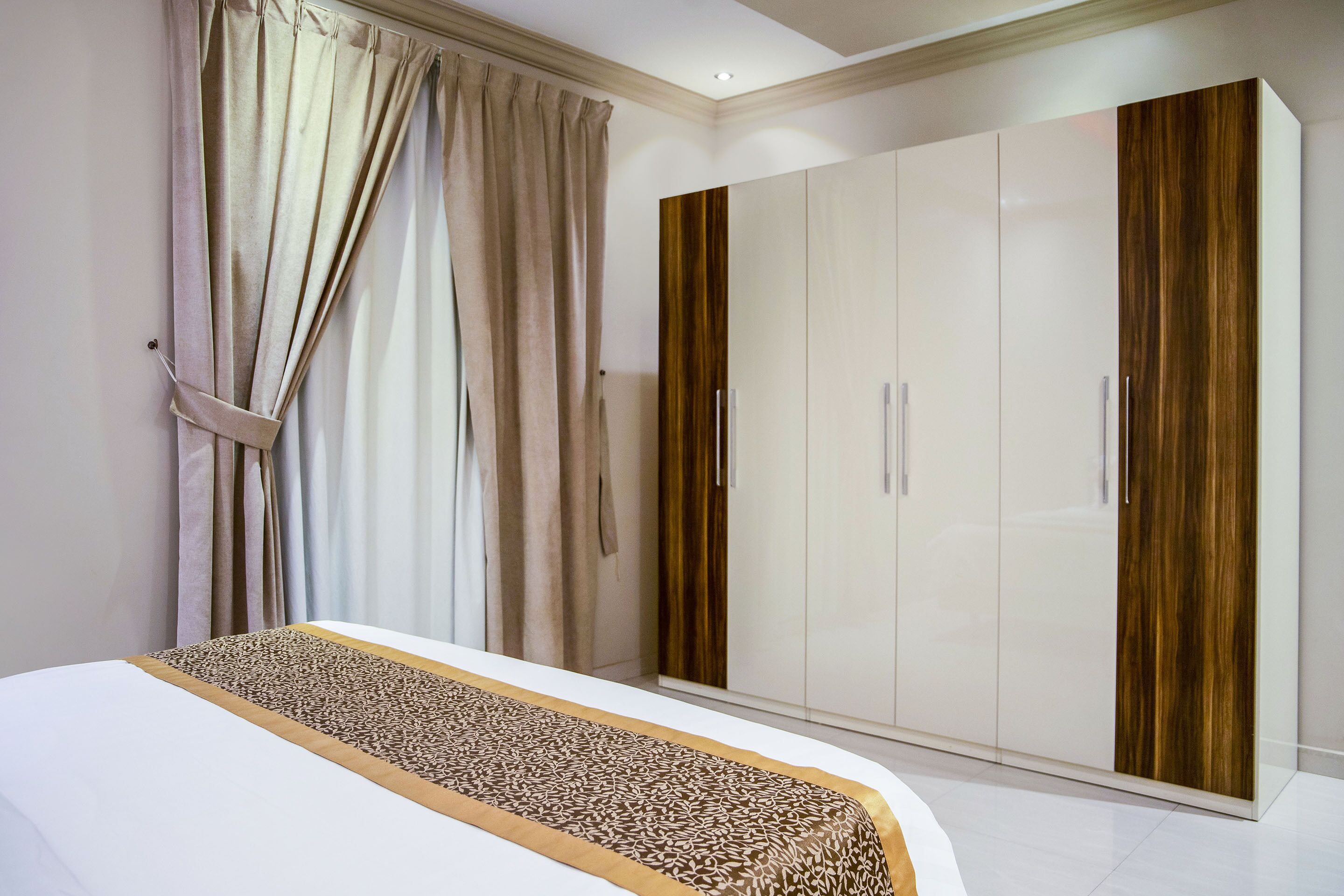 A bedroom with a bed, a wardrobe, and curtains.