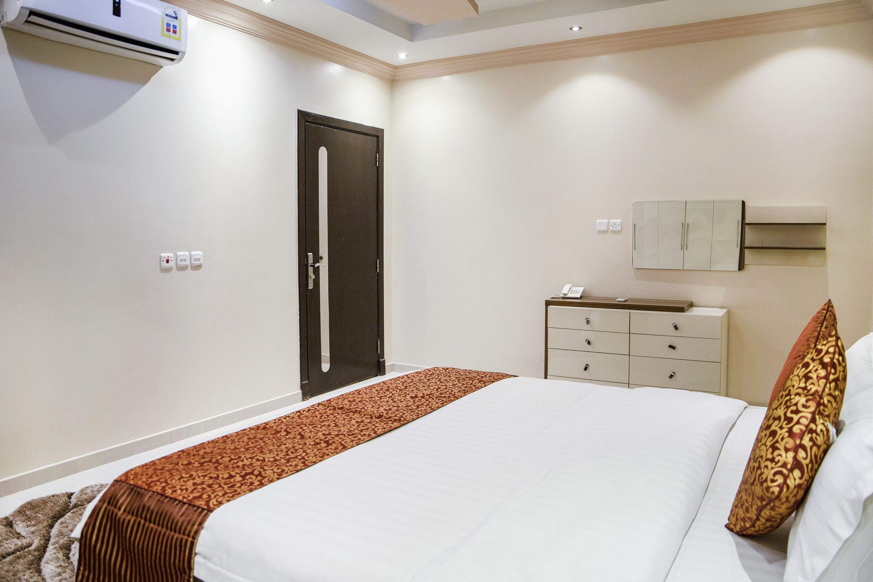 Una habitación de hotel con cama, cómoda, aire acondicionado y puerta.