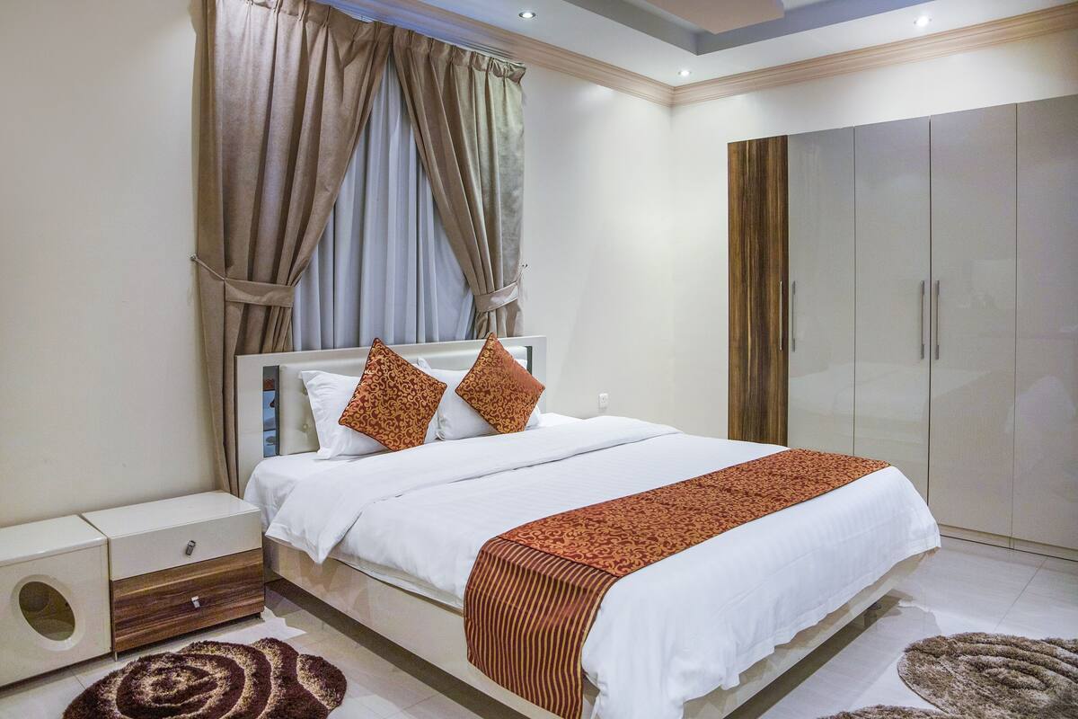 Un dormitorio moderno con una cama grande, un armario y una mesita de noche.