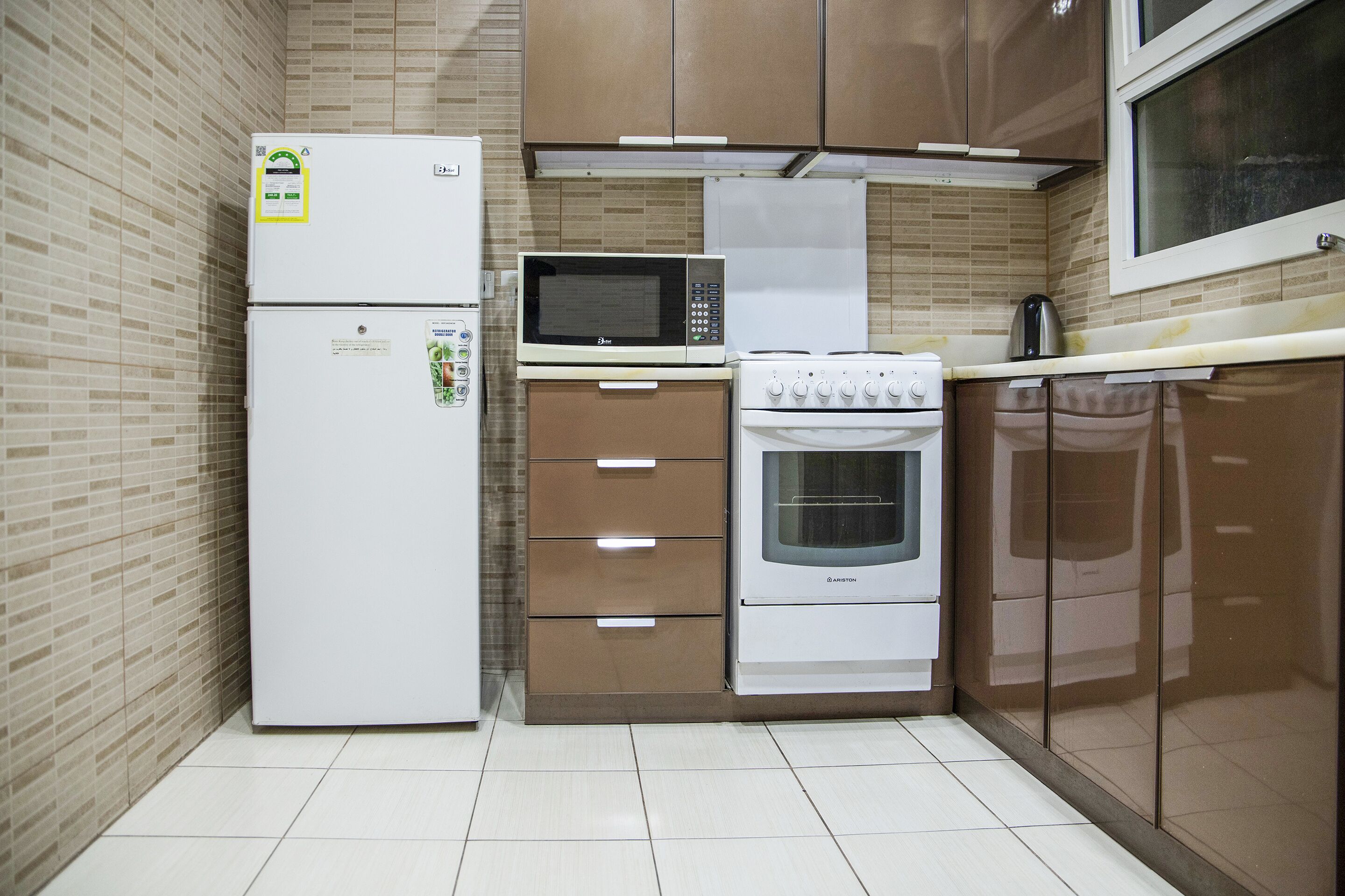 A compact kitchen with a refrigerator, microwave, oven, and a stove.