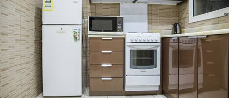 A compact kitchen with a refrigerator, microwave, oven, and a stove.