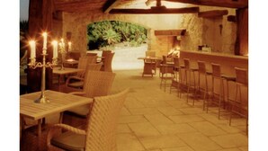 An indoor dining area with wooden tables and chairs, a stone wall, and a fireplace.