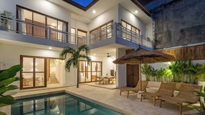 A modern two-story house with a swimming pool, outdoor seating, and a staircase leading to the upper floor. - Villa Milos (Canggu)
