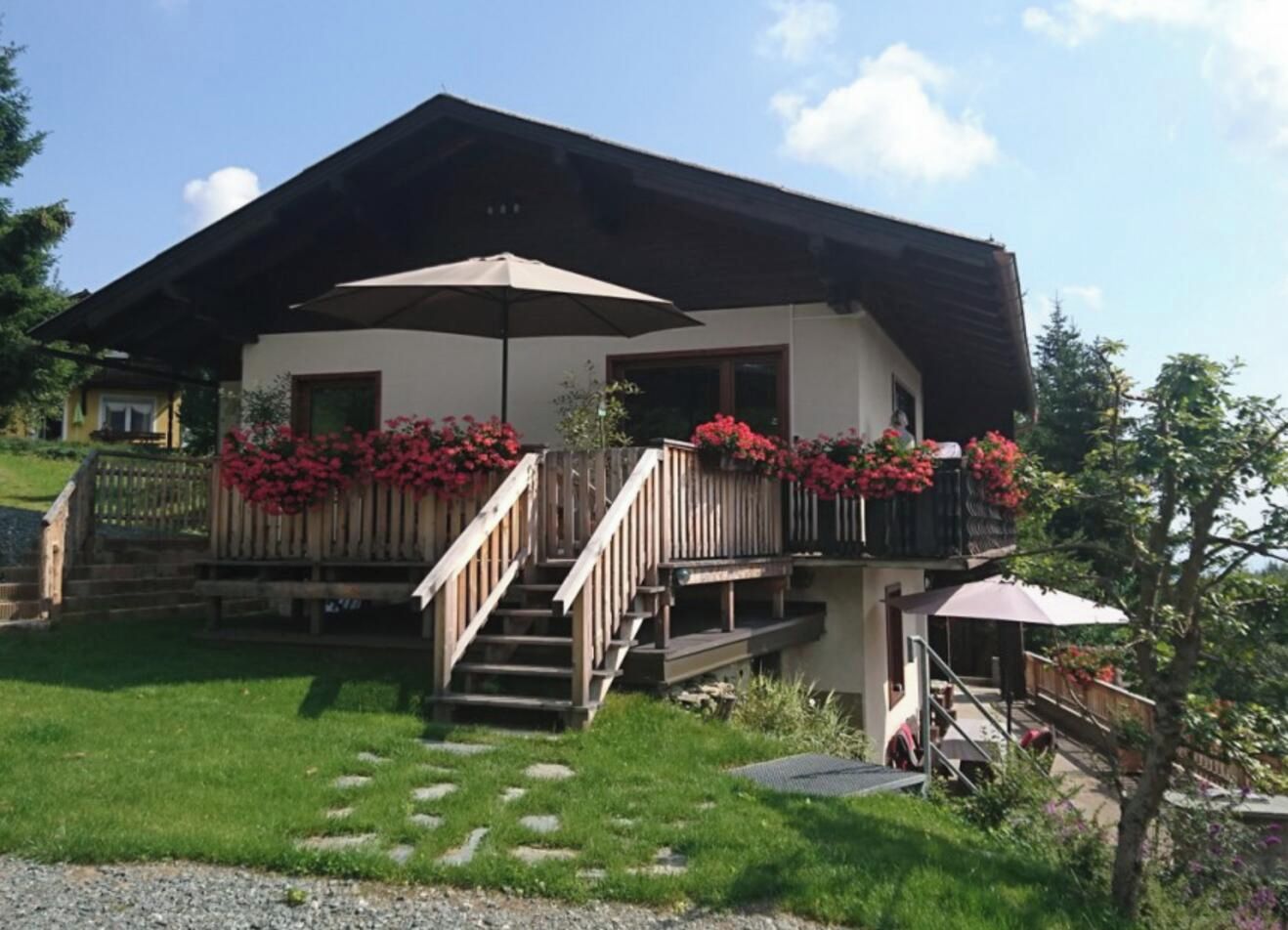 Eine zweistöckige Chalet mit einer Holztreppe, einer Veranda und Blumenkästen.