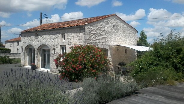 Un bâtiment en pierre avec un toit en tuiles, des fenêtres en arc de cercle et un petit porche.