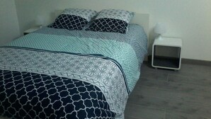 Une chambre à coucher avec un lit, une table de chevet et un panier pour animal de compagnie.