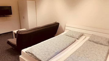 A hotel room with a bed, a chair, a wardrobe, and a TV.