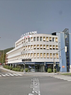 A building with the sign VOLKSBANK and AXFLOW on the facade. - Veni Apartments (Graz)