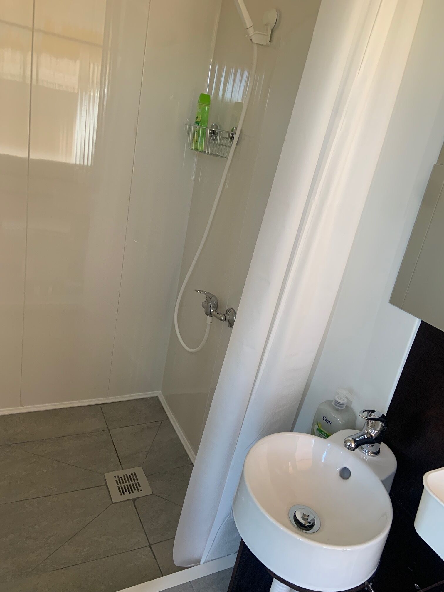 A bathroom with a shower, a sink, and toiletries.