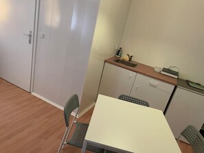 A compact kitchen with a sink, cabinets, and a table with two chairs. - Veni Apartments (Graz)