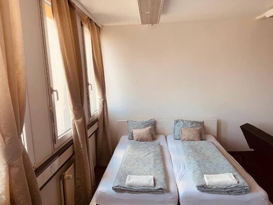 A double bed room with two beds, a window with curtains, and a radiator.