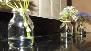 Three glass vases with flowers on a reflective black countertop. - Coventry Park House (Coventry)