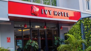 The exterior of the Ivy Hotel with a red and white facade, large windows, and a balcony with greenery. - Ivy Hotel Emerald (Lagos)