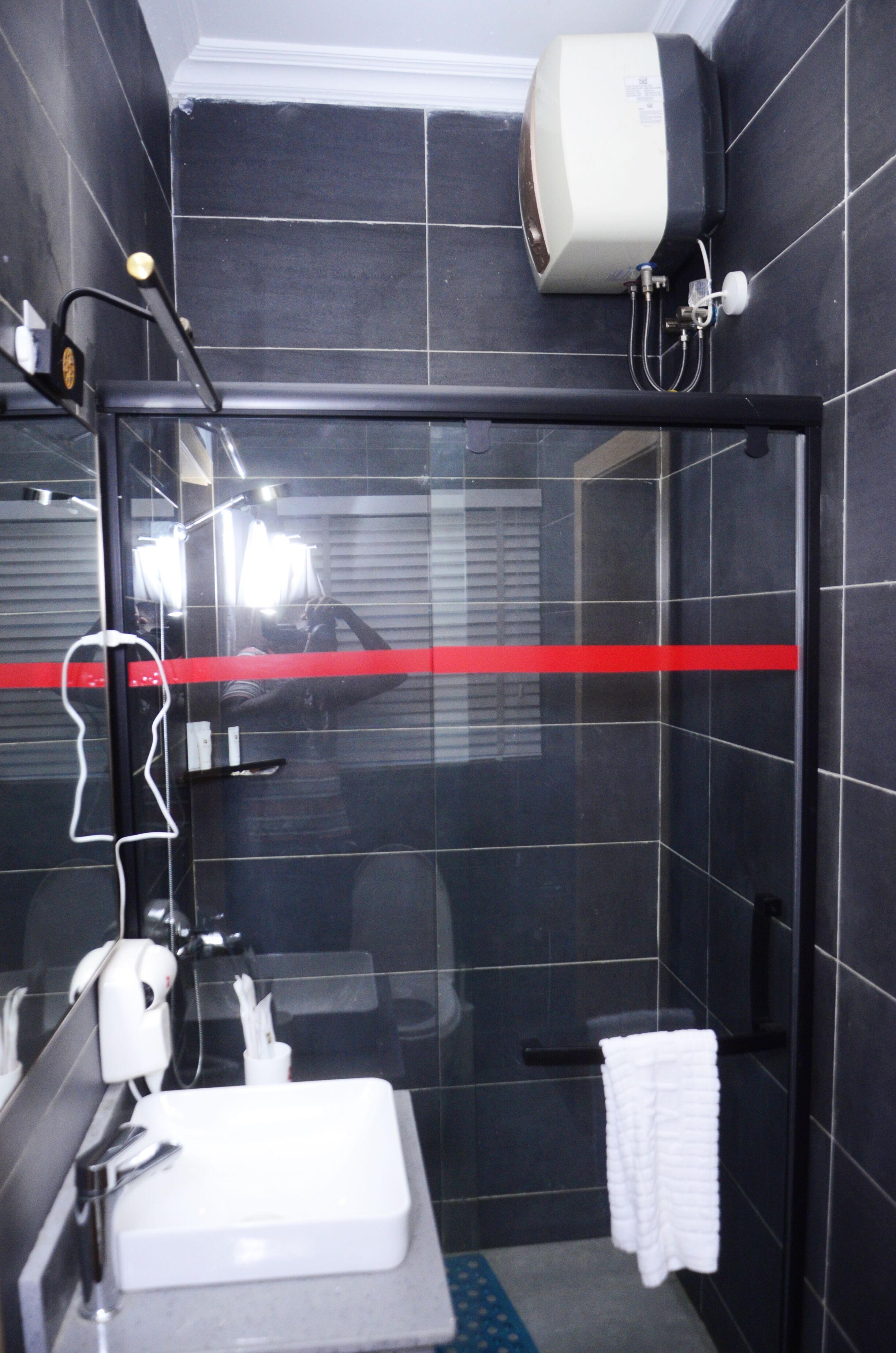 Un baño moderno con ducha de vidrio, lavamanos blanco y toallero.