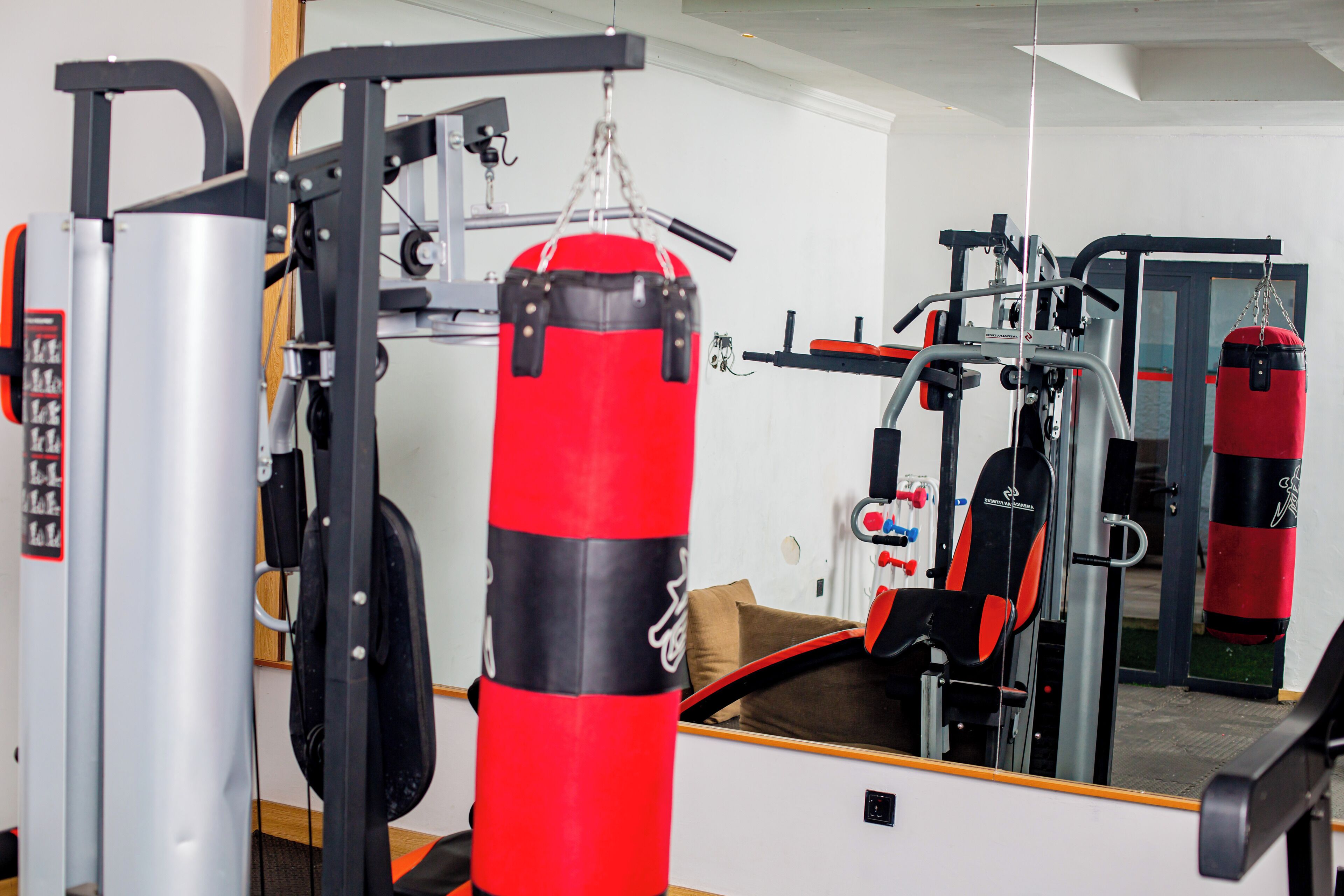 A gym with various exercise equipment, including a punching bag, weight machines, and a bench.