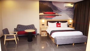 A hotel room with a bed, a sofa, a small table, and a chair. - Ivy Hotel Emerald (Lagos)