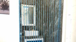 Eine kleine, abgeschlossene Duschkabine mit blau-weißen Fliesen, einem Spiegel und einem Duschvorhang mit Wellenmuster.